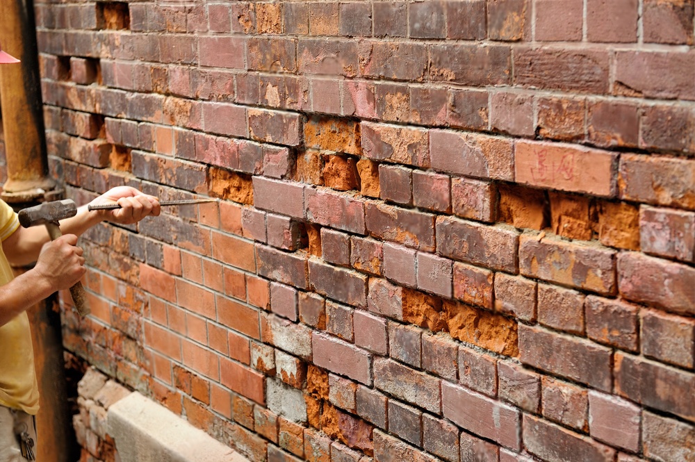 repairing old brick wall using hammer